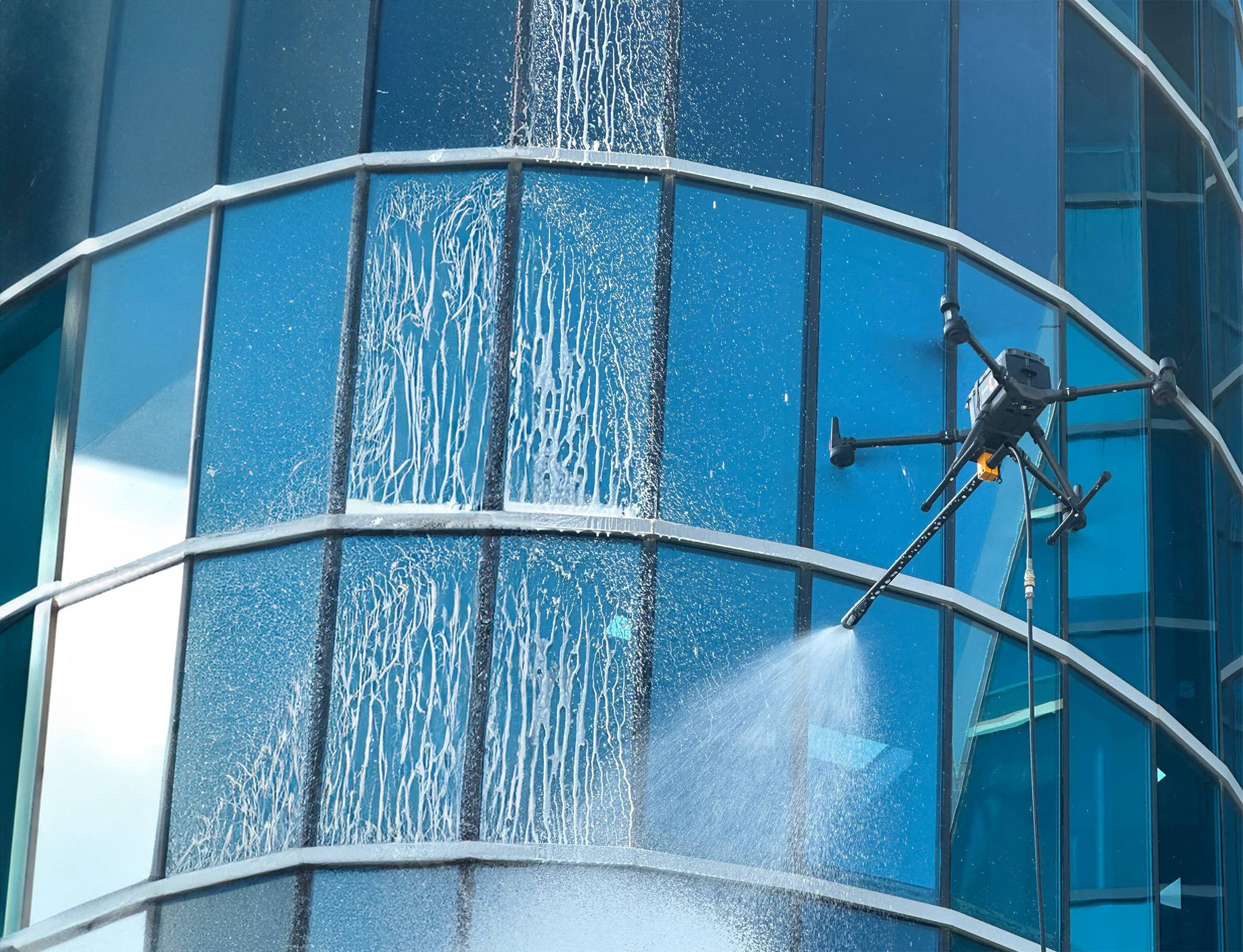 Dron netejant la façana de vidre d'un edifici amb aigua a pressió